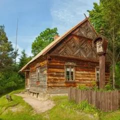 Drewniane chaty i kapliczka na słupie w jednym z urokliwych skansenów w Polsce.