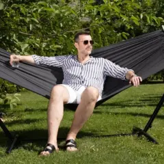 Mężczyzna w okularach relaksuje się w czarnym hamaku na trawie. Idealny wybór, by odpocząć w ogrodzie.