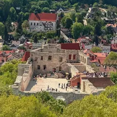 Ruiny zamku w Kazimierzu Dolnym, otoczone zielenią i zabudowaniami, przyciągają turystów.