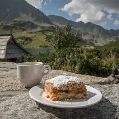 Słodka chwila w Dolinie Pięciu Stawów: szarlotka i kawa na kamieniu, w tle góry i schronisko.