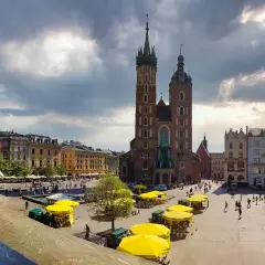 Małe dziecko na tle Rynku Głównego w Krakowie. Wspaniałe miejsce, by zobaczyć, co można robić w Krakowie: zwiedzać, spacerować, podziwiać architekturę.