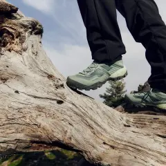 Zielone buty w góry na drewnianym pniu, gotowe na przygodę.