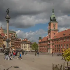 Kolumna Zygmunta i Zamek Królewski na placu w Warszawie. Wiele osób spaceruje, odkrywając warszawskie atrakcje.