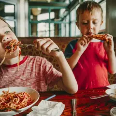 Dwóch chłopców zajada spaghetti i pizzę. Szukasz miejsca, gdzie zjeść w Kołobrzegu?