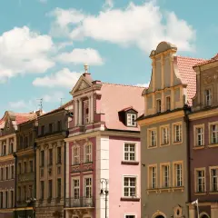 Kolorowe kamienice na Rynku w Poznaniu, piękne poznańskie zabytki pod błękitnym niebem z chmurami.