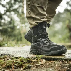 Czarne, wysokie buty trekkingowe z membraną HydroGuard na mokrej, kamienistej ścieżce. Idealne na trudne warunki.