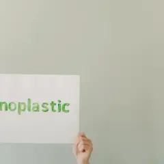 Ręce trzymają kartkę z napisem #noplastic. To apel o turystykę zrównoważoną i świadome wybory.