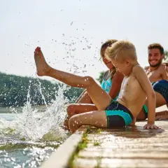 Rodzina pluska się w jeziorze, tworząc fontanny wody. Idealne fajne miejsce na wakacje z dzieckiem w Polsce.