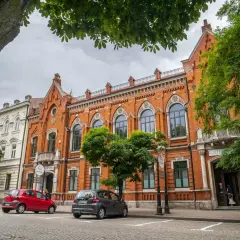 Kamienice w Radomiu, w tym Bank Polski, to ciekawe **radom atrakcje**. Dwa samochody zaparkowane na brukowanej ulicy.