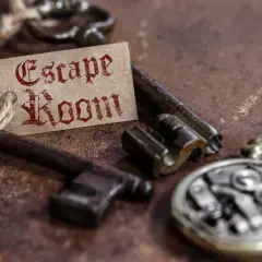 Stare klucze i przywieszka z napisem "Escape Room" na rustykalnym tle.