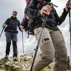 Dwie osoby wędrują po skalistym szlaku, używając kijków w góry dla wsparcia.