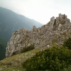 Sarnia góra wznosi się dumnie, skaliste szczyty przyciągają wzrok. Na górze widać ludzi podziwiających panoramę.