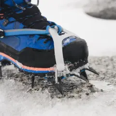 Buty z rakami w podeszwie, gotowe na lodowe wspinaczki. Kolce pewnie trzymają się skały pokrytej śniegiem.