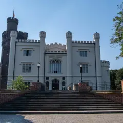 Biały pałac z wieżą, jeden z pięknych zamków w Wielkopolsce, strzeżony przez kamienne lwy.