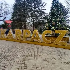 Złote litery KARPACZ w centrum, obok choinki, tworzą świąteczną atmosferę.