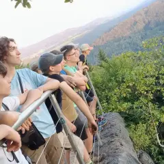 Grupa młodych ludzi podziwia widok z góry. To właśnie jest trekking – przygoda i odkrywanie piękna natury.