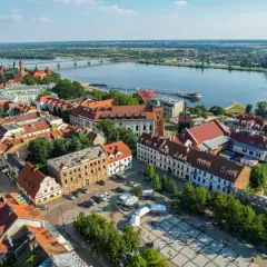 Widok na Wisłę i zabytkowe centrum Płocka. Widać most, katedrę i urokliwe kamienice, które tworzą niepowtarzalne atrakcje Płocka.