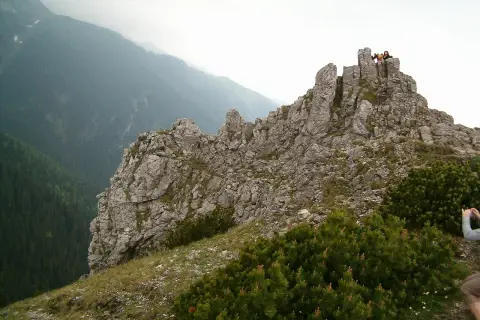 Sarnia góra wznosi się dumnie, skaliste szczyty przyciągają wzrok. Na górze widać ludzi podziwiających panoramę.
