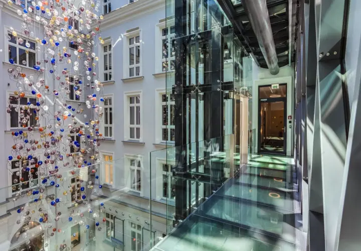 Nowoczesny dziedziniec hotelowy z instalacją szklanych kul i przeszklonymi korytarzami. Idealne miejsce na city break w Polsce.
