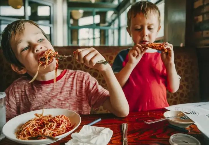 Dwóch chłopców zajada spaghetti i pizzę. Szukasz miejsca, gdzie zjeść w Kołobrzegu?