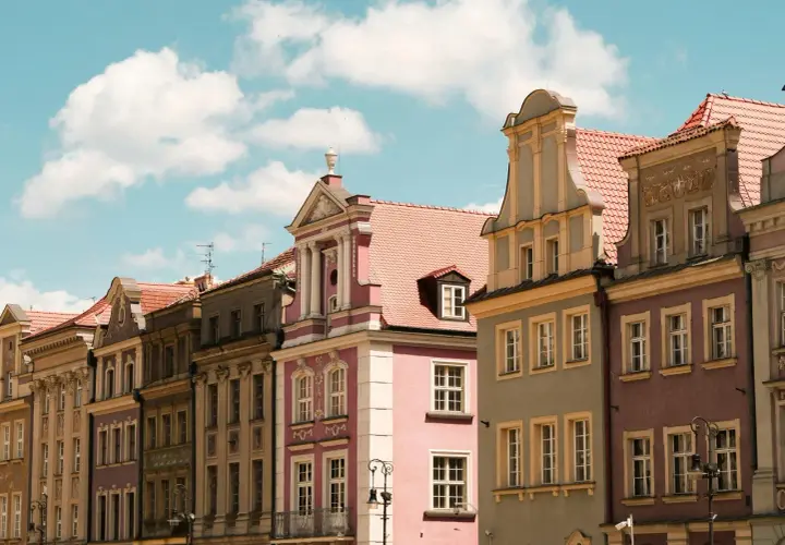 Kolorowe kamienice na Rynku w Poznaniu, piękne poznańskie zabytki pod błękitnym niebem z chmurami.