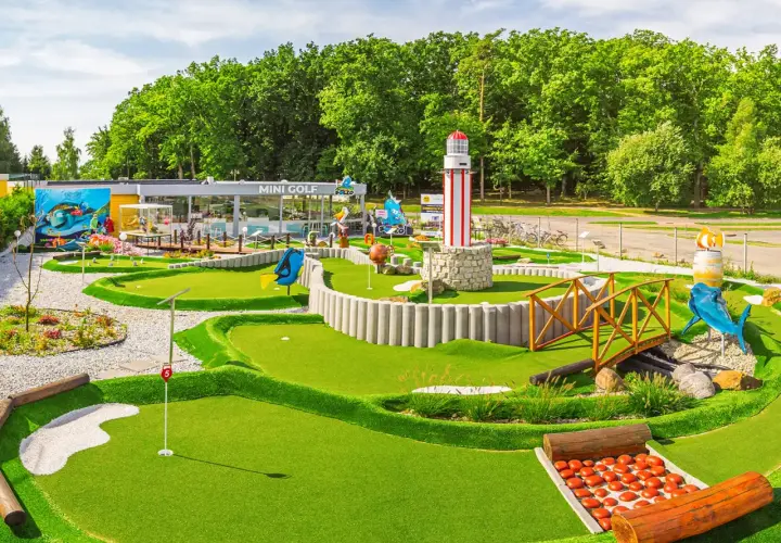 Mini golf w Rewalu to świetna zabawa! Wesołe dekoracje, w tym latarnia morska i rekin, zachęcają do gry.