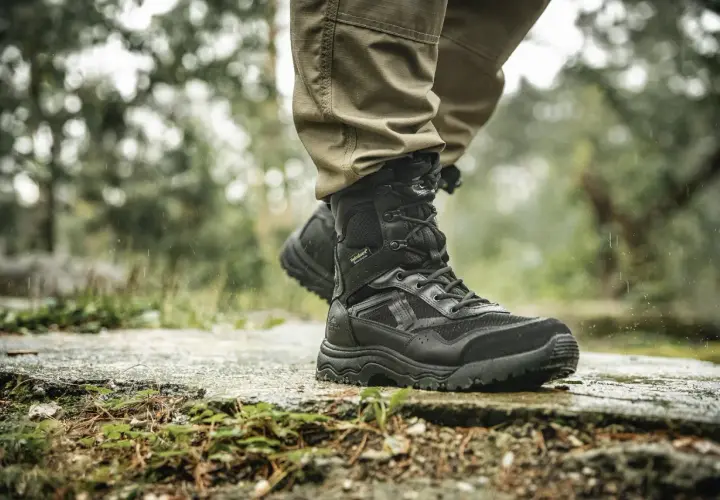 Czarne, wysokie buty trekkingowe z membraną HydroGuard na mokrej, kamienistej ścieżce. Idealne na trudne warunki.