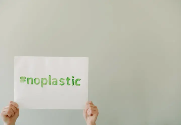 Ręce trzymają kartkę z napisem #noplastic. To apel o turystykę zrównoważoną i świadome wybory.