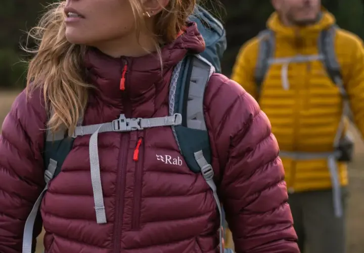 Dwie osoby w kurtkach puchowych Rab, gotowe na wędrówkę. Rab to firma tworząca odzież outdoorową.