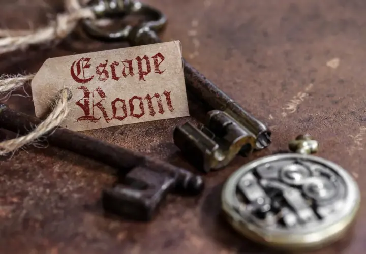 Stare klucze i przywieszka z napisem "Escape Room" na rustykalnym tle.