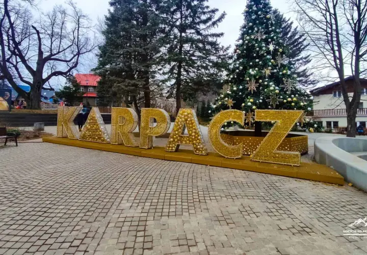 Złote litery KARPACZ w centrum, obok choinki, tworzą świąteczną atmosferę.