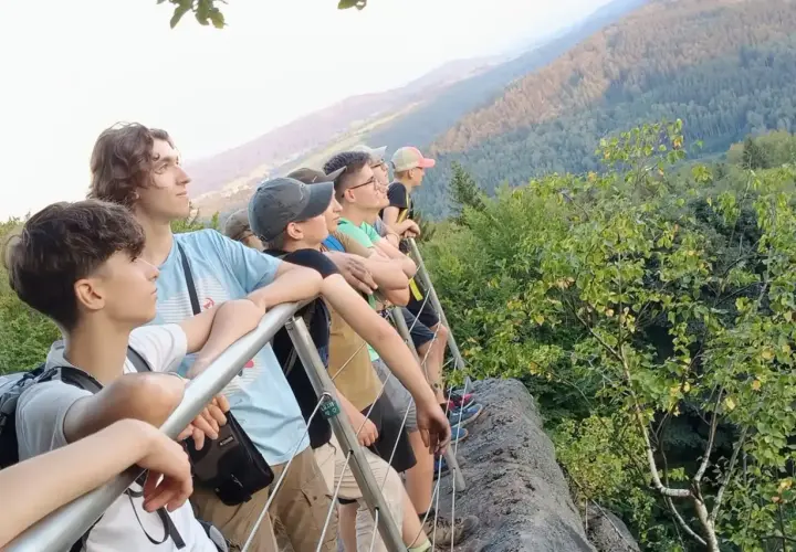 Grupa młodych ludzi podziwia widok z góry. To właśnie jest trekking – przygoda i odkrywanie piękna natury.