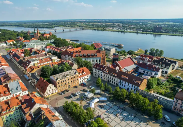 Widok na Wisłę i zabytkowe centrum Płocka. Widać most, katedrę i urokliwe kamienice, które tworzą niepowtarzalne atrakcje Płocka.