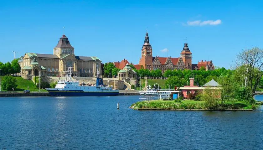 Widok na Odrę i zabytkowe budynki, w tym Muzeum Narodowe, to jedne z głównych atrakcji Szczecina. Statek "Navigator XXI" zacumowany przy nabrzeżu.
