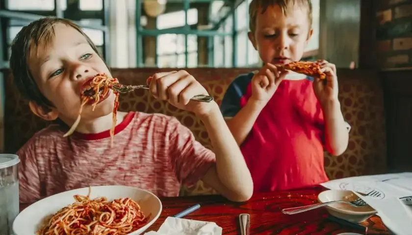 Dwóch chłopców zajada spaghetti i pizzę. Szukasz miejsca, gdzie zjeść w Kołobrzegu?