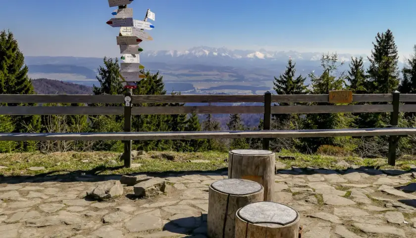Słup z drogowskazami turystycznymi w pobliżu parkingu na Turbaczu. W tle piękne widoki na Tatry.