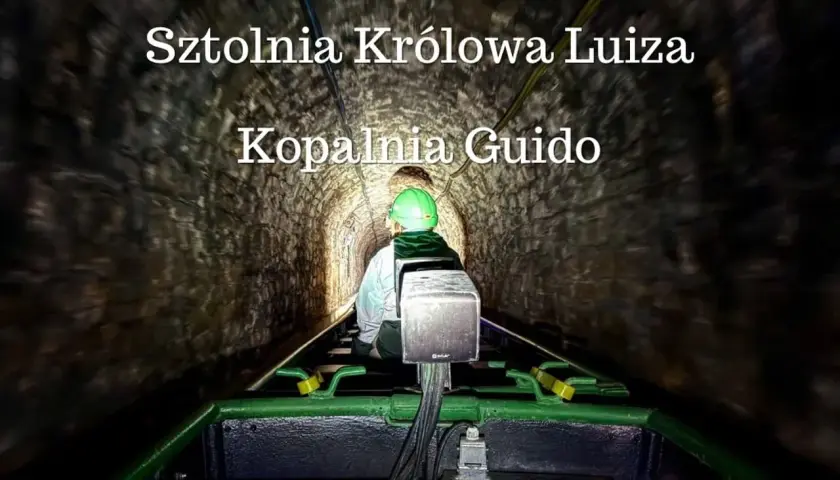 Osoba w kasku jedzie kolejką w ciemnej sztolni Królowa Luiza, Kopalnia Guido.