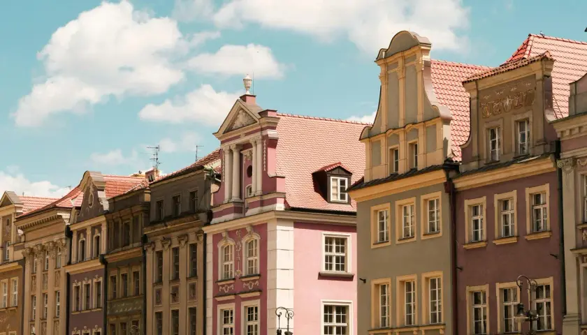 Kolorowe kamienice na Rynku w Poznaniu, piękne poznańskie zabytki pod błękitnym niebem z chmurami.