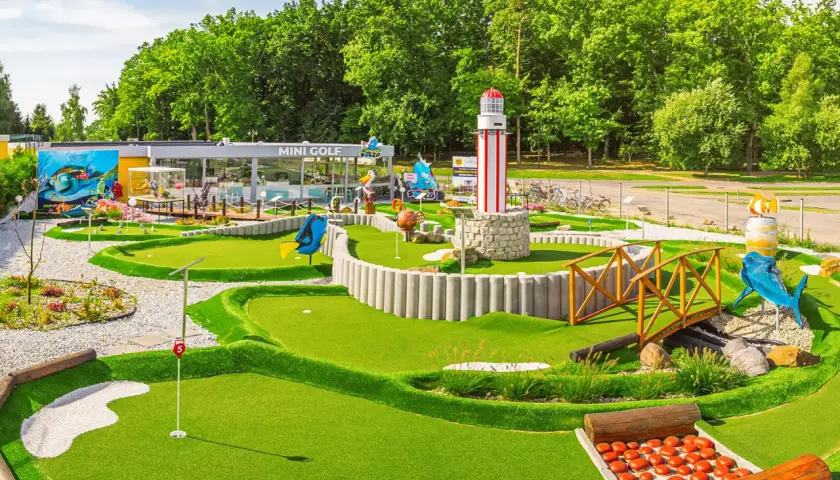 Mini golf w Rewalu to świetna zabawa! Wesołe dekoracje, w tym latarnia morska i rekin, zachęcają do gry.