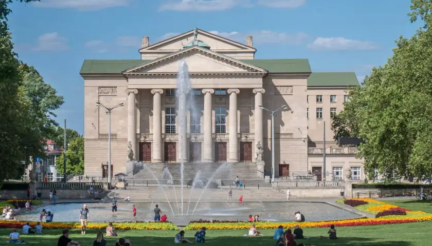 Poznań atrakcje dla młodzieży: ludzie odpoczywają przy fontannie przed Teatrem Wielkim.