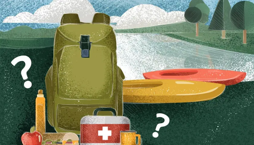 Co zabrać na kajaki? Plecak, apteczka, jedzenie, napój i jabłko czekają obok dwóch kajaków.