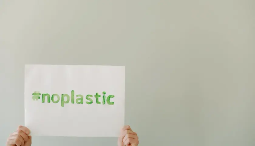 Ręce trzymają kartkę z napisem #noplastic. To apel o turystykę zrównoważoną i świadome wybory.