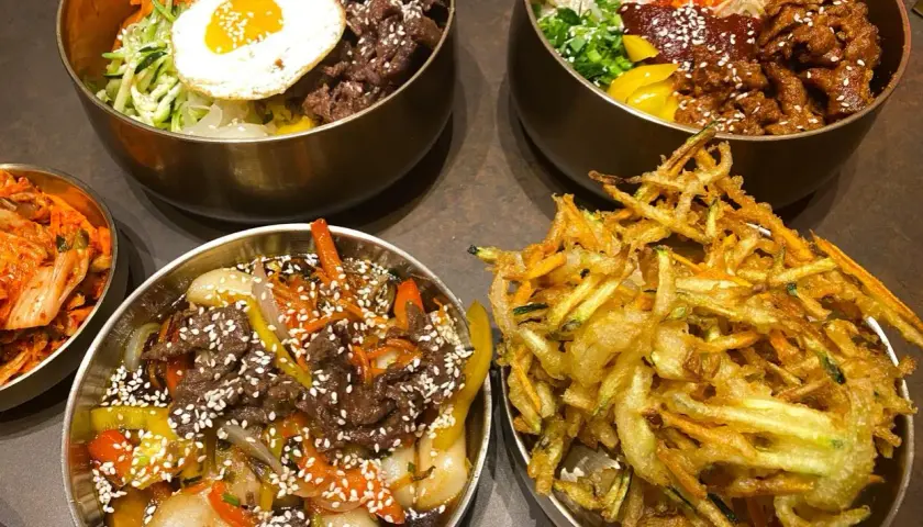 Pyszne dania kuchni koreańskiej, idealne dla polecanych restauracji w Poznaniu: bibimbap, bulgogi i chrupiące warzywa w cieście.