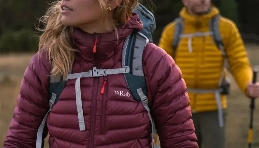 Dwie osoby w kurtkach puchowych Rab, gotowe na wędrówkę. Rab to firma tworząca odzież outdoorową.