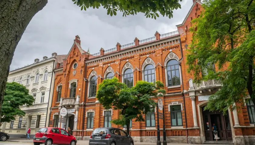 Kamienice w Radomiu, w tym Bank Polski, to ciekawe **radom atrakcje**. Dwa samochody zaparkowane na brukowanej ulicy.
