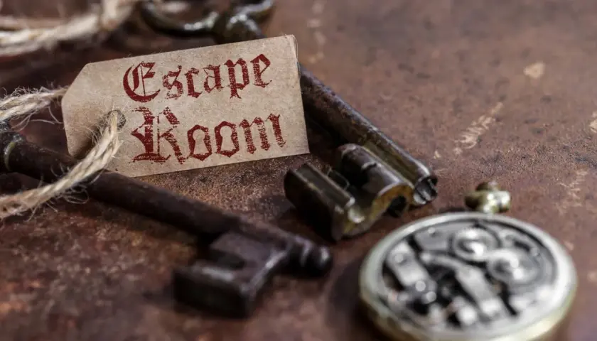 Stare klucze i przywieszka z napisem "Escape Room" na rustykalnym tle.