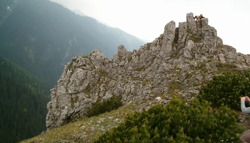 Sarnia góra wznosi się dumnie, skaliste szczyty przyciągają wzrok. Na górze widać ludzi podziwiających panoramę.
