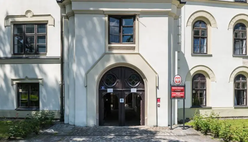 Wejście do zabytkowego zamku w Żywcu, z charakterystycznymi drzwiami i oknami. Obok tablica informująca o Muzeum Miejskim i Urzędzie Stanu Cywilnego.