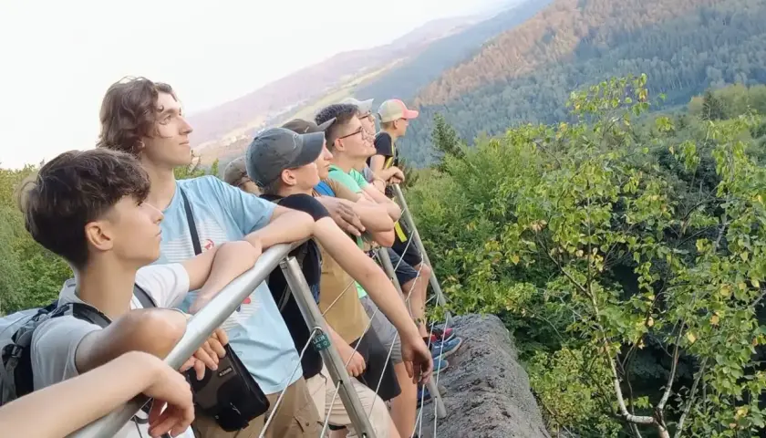 Grupa młodych ludzi podziwia widok z góry. To właśnie jest trekking – przygoda i odkrywanie piękna natury.