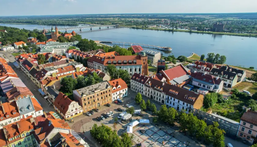 Widok na Wisłę i zabytkowe centrum Płocka. Widać most, katedrę i urokliwe kamienice, które tworzą niepowtarzalne atrakcje Płocka.
